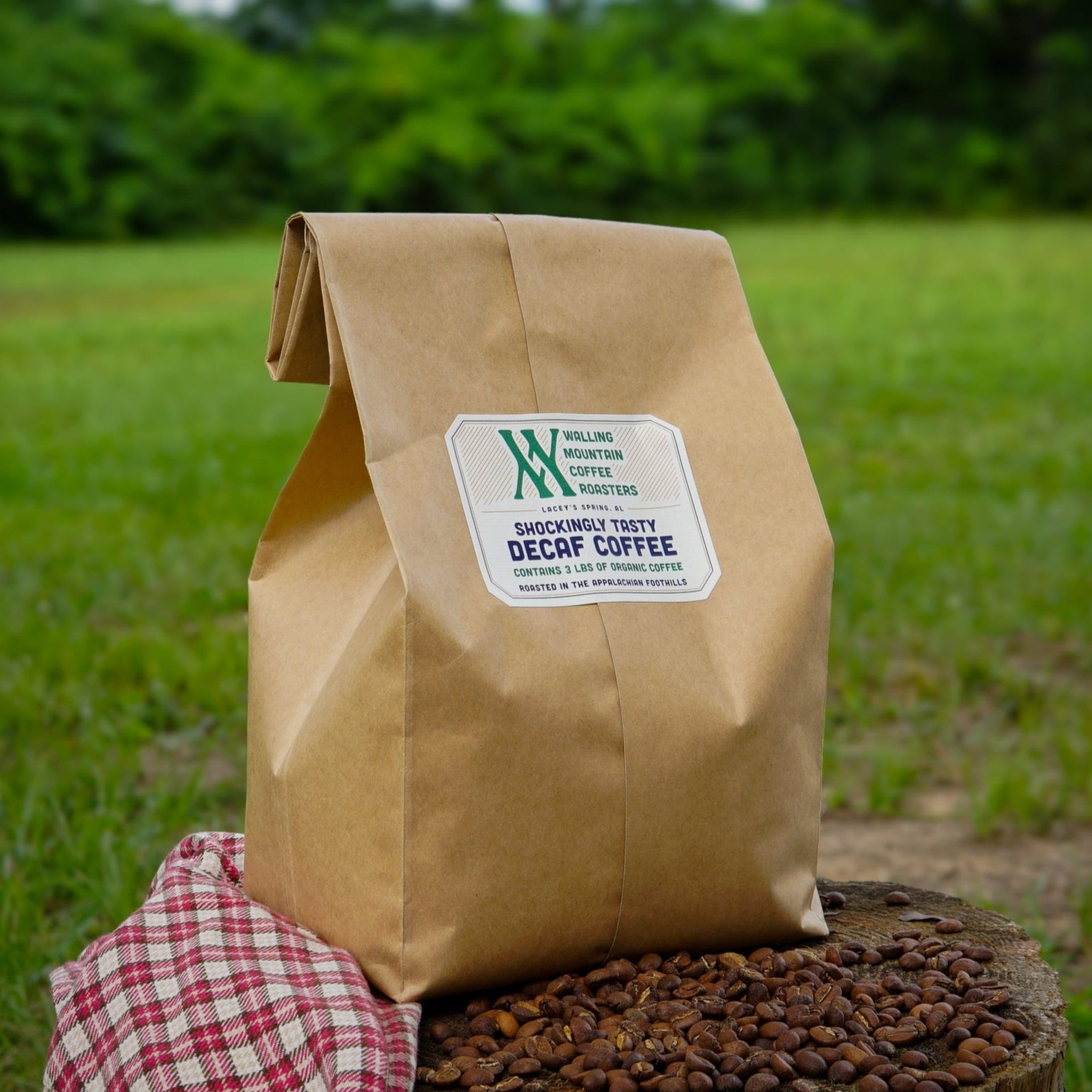 Brown paper bag of coffee with a Walling Mtn. Coffee Roasters brand label on a wooden stump outdoors.